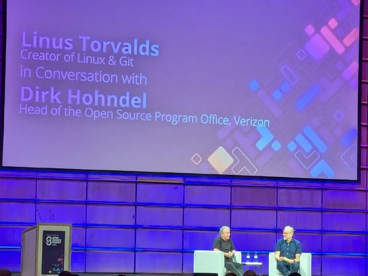 Linus Torvalds e Dirk Hohndel seduti sul palco dell'Open Source Summit Europe 2024 a Vienna, sotto uno schermo con i loro nomi